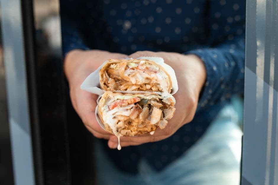 Delicious chicken wrap held by hand with fresh ingredients